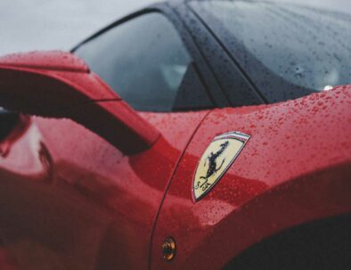 Red Ferrari with side logo in a rainy day - Timeless Tuscany services