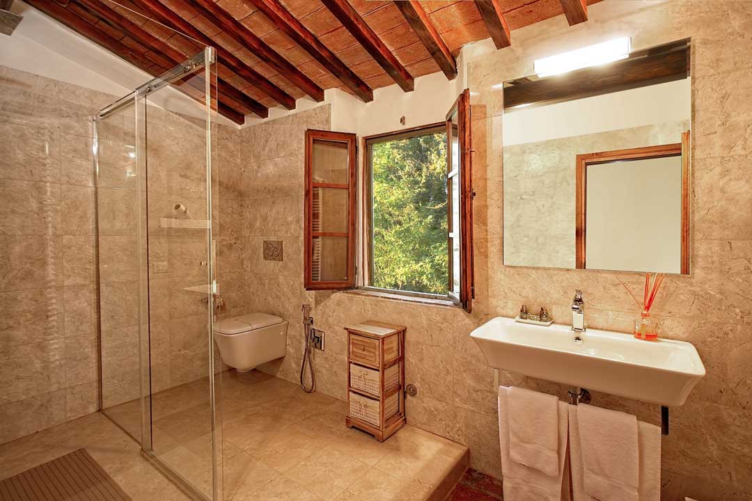 Italy Villa Bellavista Certaldo Chianti; bathroom sink and wc; open window overlooking trees and garden; wooden beams ceiling - villa rentals by Timeless Tuscany tour operator