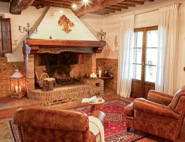 Italy Villa Bellavista Certaldo Chianti; living room with fire place and window; leather arm chairs on persian carpet; antique lamps and paintings - villa rentals by Timeless Tuscany tour operator