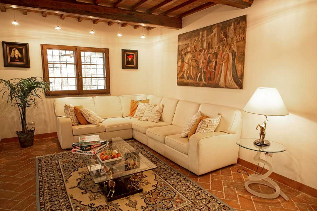Italy Villa Bellavista Certaldo Chianti; living room with white sofa and window; coffee table, persian carpet; antique lamp and paintings - villa rentals by Timeless Tuscany tour operator