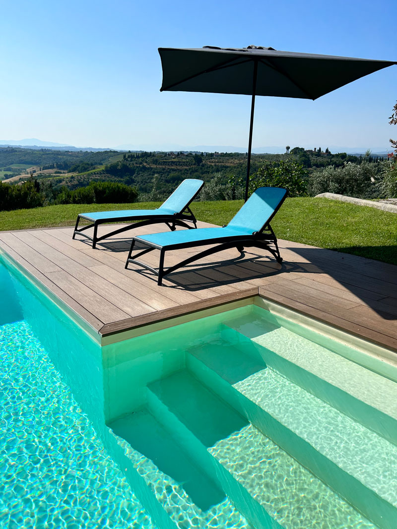 Villa Bellavista swimming pool; deck with lounge chair and umbrella in sunny day - villa rentals by Timeless Tuscany tour operator
