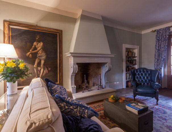 Villa dei Fiori living room with sofa, table lamp and chimney - by Timeless Tuscany villas rentals