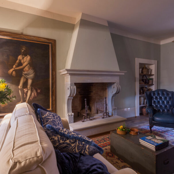 Villa dei Fiori living room with sofa, table lamp and chimney - by Timeless Tuscany villas rentals