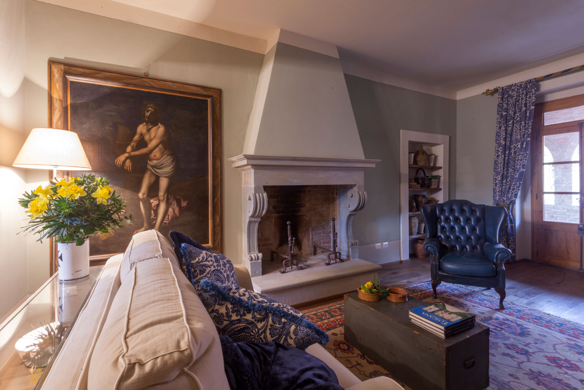 Villa dei Fiori living room with sofa, table lamp and chimney - by Timeless Tuscany villas rentals